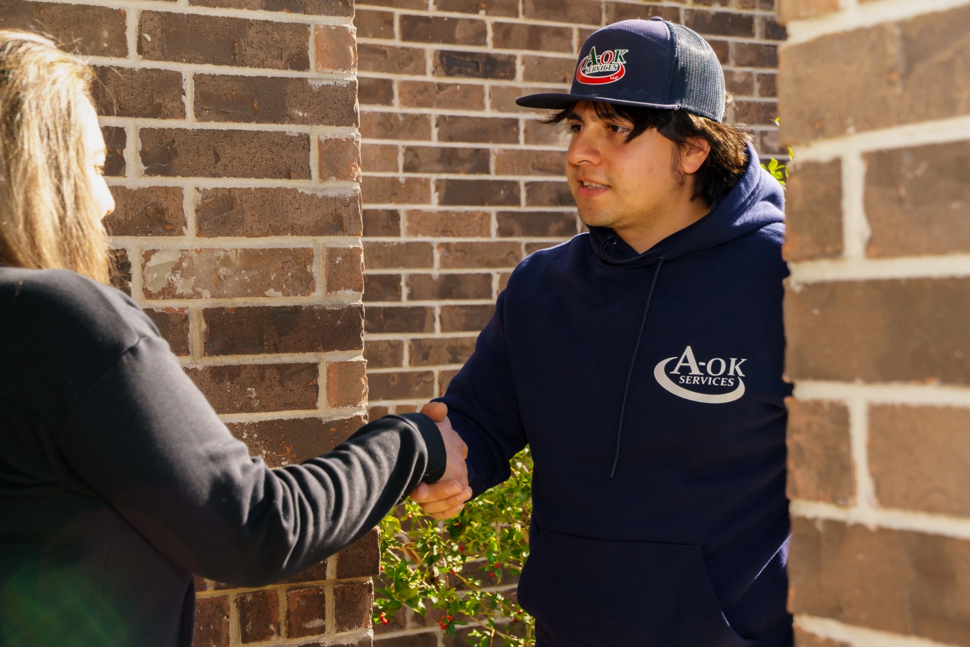 Técnico de climatización de A-OK Services consultando con cliente sobre instalación nueva de aire acondicionado en San Antonio